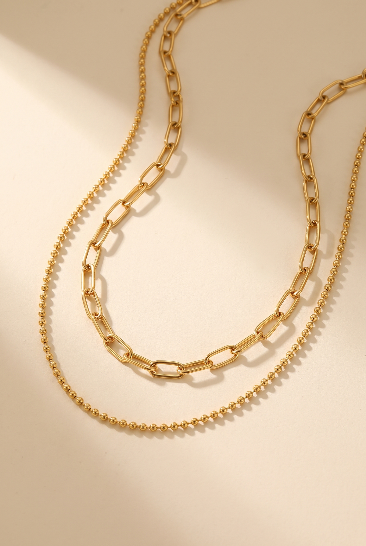 Dani gold layered chain necklace set on a warm cream surface